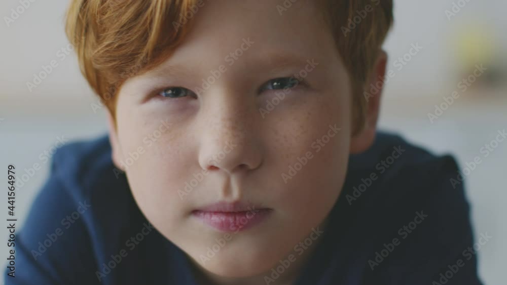 Kids eyesight problems. Little redhead boy with freckles squinting eyes, peering to camera, feeling troubles with vision Kids eyesight problems. Little redhead boy with freckles squinting eyes, peering to camera, feeling troubles with vision
