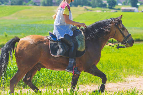 Competitor rival girl riding horse in summer field meadow.Young rider gallops through the summer sunny day.