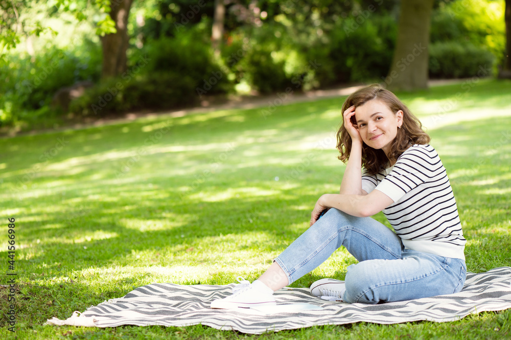 Happy pretty woman resting on blanket in park Happy pretty woman resting on blanket in park