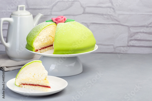 Traditional Swedish dessert Princess cake with green marzipan cover and pink rose decoration, on  gray background, horizontal, copy space photo