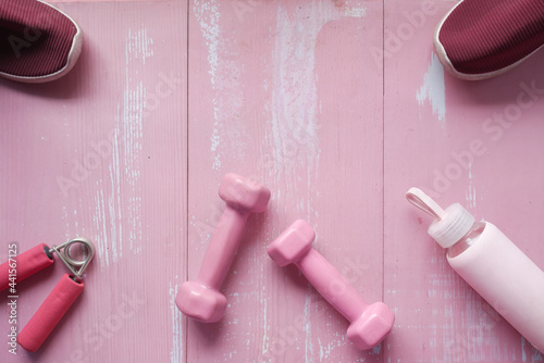  pink color dumbbell, shoe and headphone on pink background 
