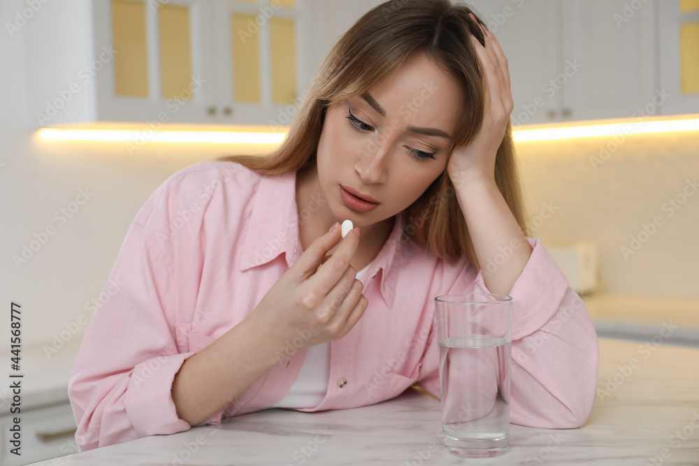 Young woman taking abortion pill in kitchen Young woman taking abortion pill in kitchen