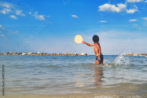 A child plays in the sea with paddle and ball