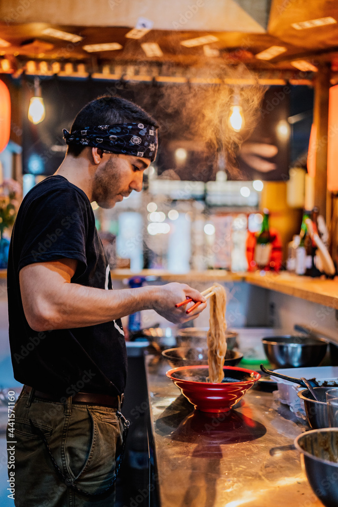 Man in bandana standing at counter and cooking ramen Man in bandana standing at counter and cooking ramen