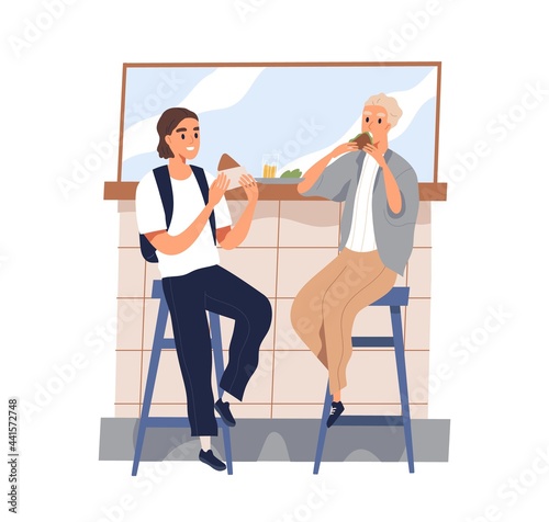 Friends meeting and eating out together. Young men sitting on bar stools with...