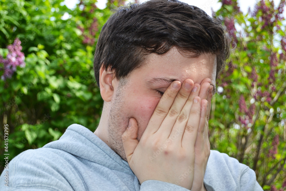 sad young man covers his face, desperate man crying, side view, depressed guy in the park sad young man covers his face, desperate man crying, side view, depressed guy in the park