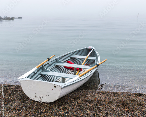 Traditional wooden rowboat sitting on a beach in fog with traditional wooden oars.  Shot in the Toronto Beaches in June.