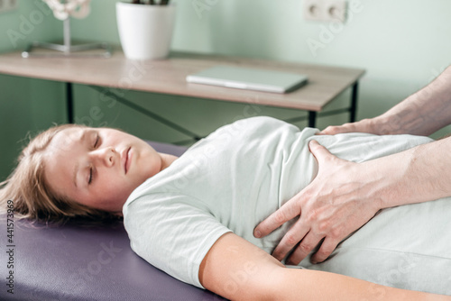 Osteopath practitioner releasing the diaphragm of a female patient, rib cage release massage, breathing muscle relaxation