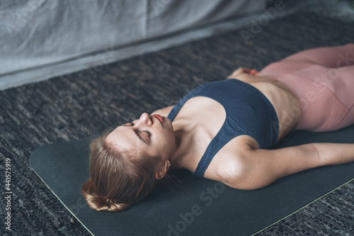 Sporty and healthy woman lying in savasana meditation pose