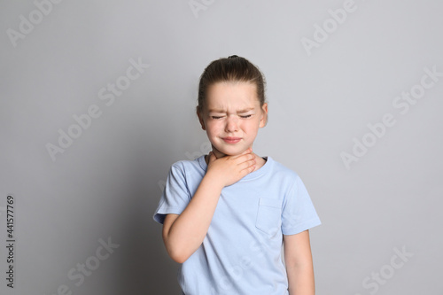 Foto Little girl suffering from sore throat on grey background