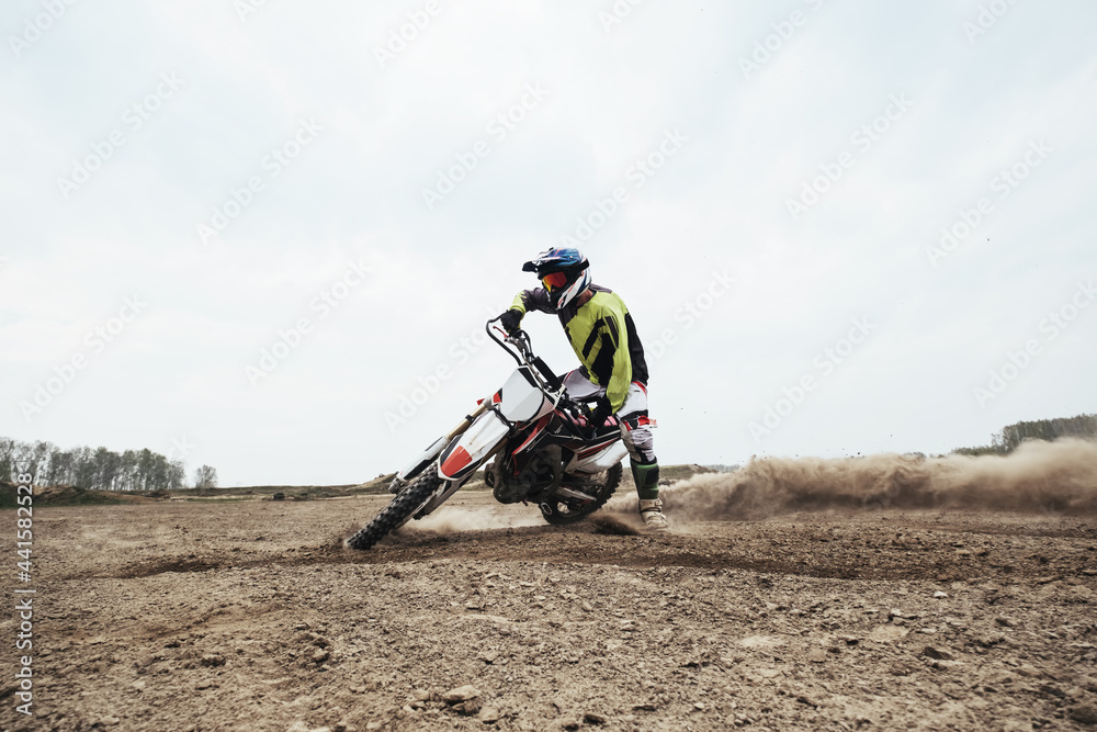 Motorcyclist jumping and riding on rear wheel at enduro motocross training ground Motorcyclist jumping and riding on rear wheel at enduro motocross training ground