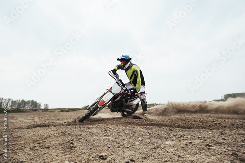 Fototapeta Naklejka Na Ścianę i Meble -  Motorcyclist jumping and riding on rear wheel at enduro motocross training ground