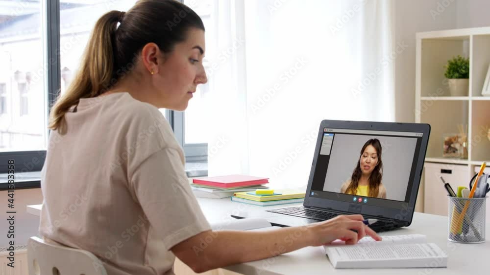 education, online school and distant learning concept - student woman with notebook and book watching tutorial video on laptop computer at home education, online school and distant learning concept - student woman with notebook and book watching tutorial video on laptop computer at home