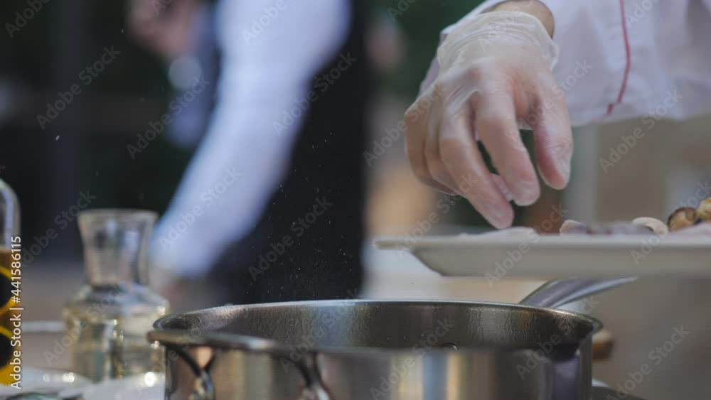 The chef on the terrace of the summer restaurant puts seafood in a frying pan. The chef on the terrace of the summer restaurant puts seafood in a frying pan.