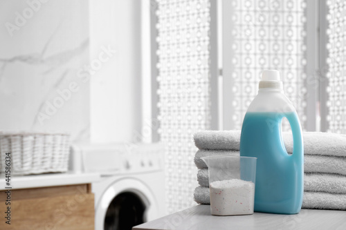 Stack of folded towels and detergents on white table in bathroom  space for text