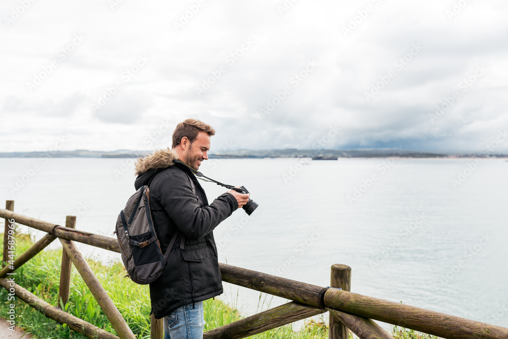 attractive Man photographing sea against overcast sky