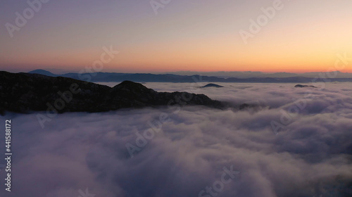 Aerial view of mesmerizing landscape of mountains of setting sun and white clouds on a warm summer evening. Concept of pristine nature and relaxation in ecologically clean corners of the planet