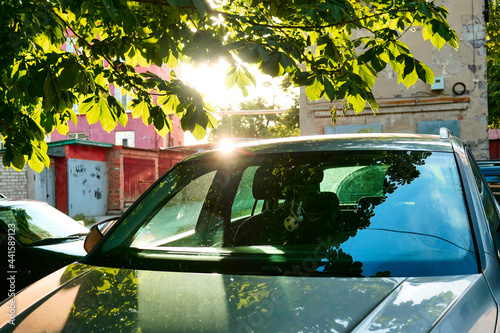 A silver SUV parked in the evening sunset. A silver car parked in the city in the sunlight.