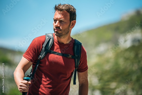Male hiker walking with trekking poles in mountainous terrain