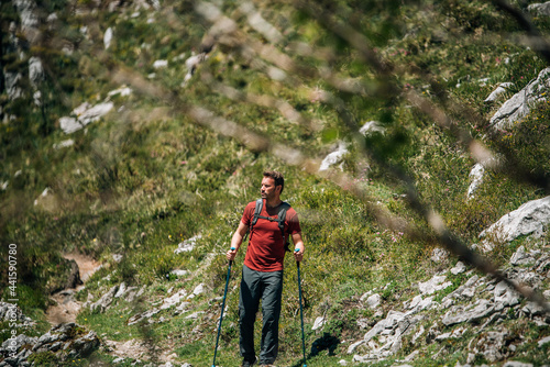 Male hiker walking with trekking poles in mountainous terrain