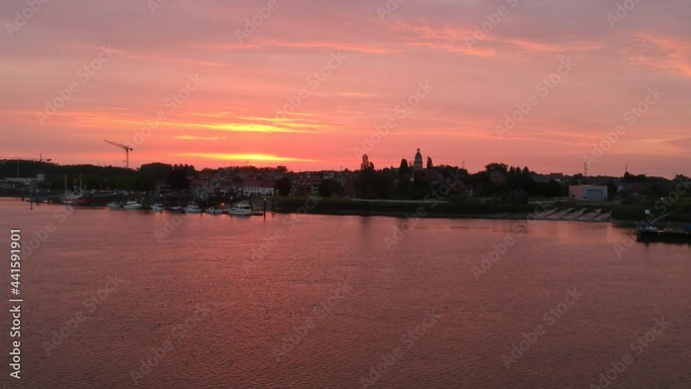 Golden color sky and city silhouette near river Schelde in aerial view Golden color sky and city silhouette near river Schelde in aerial view