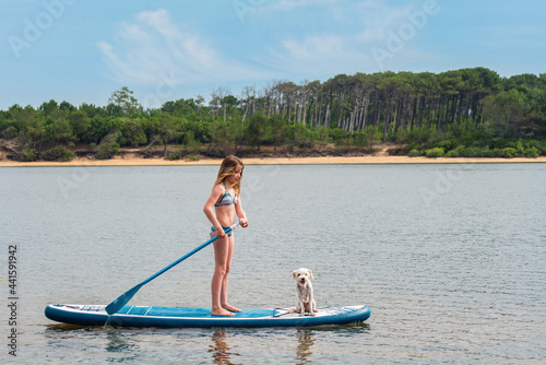 cute young girl paddle boarding with small dog