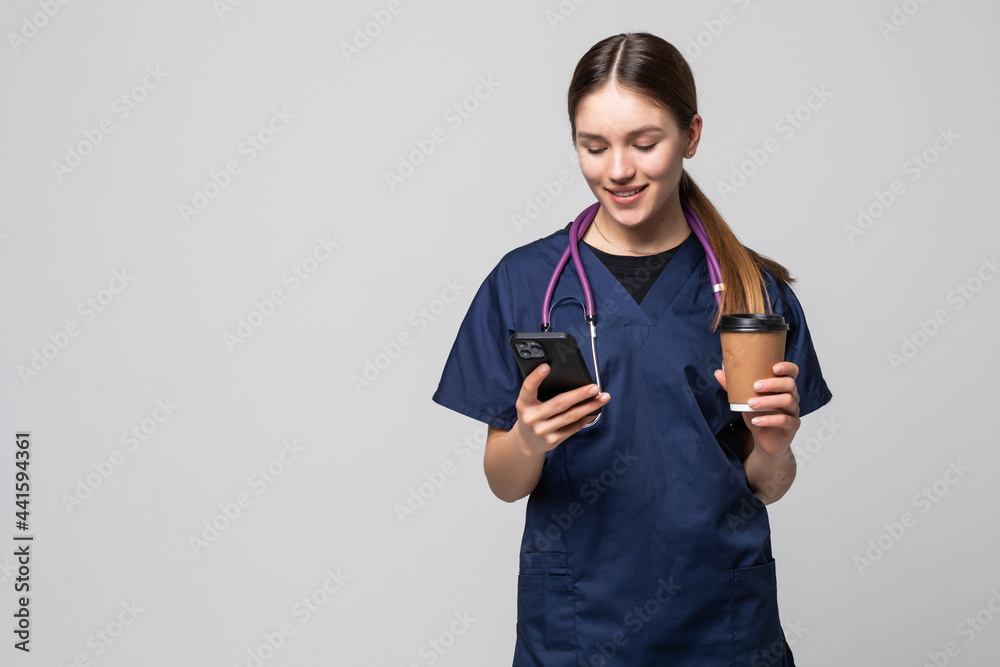 Female doctor sitting with mobile phone and drinking coffee Female doctor sitting with mobile phone and drinking coffee