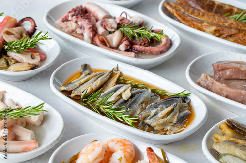 Set of Seafood Dishes. Seafood on a plate. On a white wooden background. Selective focus marinated anchovy. Lakerda, octopus salad, shrimp, fish salad