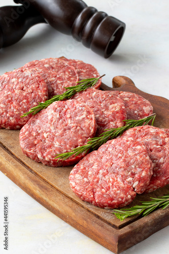 Raw beef burger patties on wooden background.