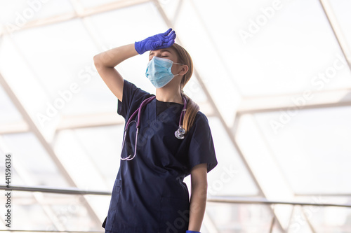 Upset nurse sitting on the floor in hospital ward. Healthcare workers in the Coronavirus Covid19 pandemic