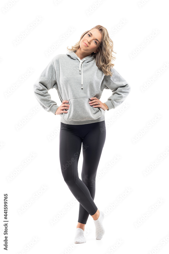 Cool happy young woman in gray sweatshirt and leggings posing with hands on hips. Full body length isolated on white background. Cool happy young woman in gray sweatshirt and leggings posing with hands on hips. Full body length isolated on white background.