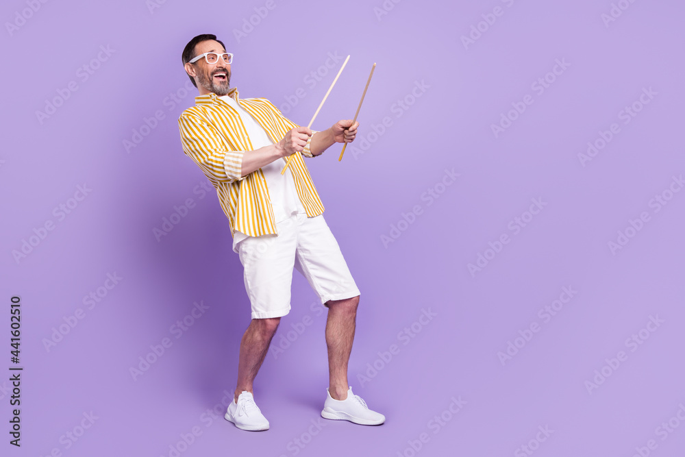 Photo of sweet funny mature man dressed striped shirt spectacles playing drums empty space smiling isolated violet color background Photo of sweet funny mature man dressed striped shirt spectacles playing drums empty space smiling isolated violet color background
