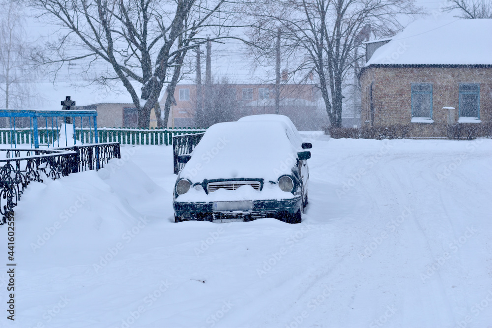 On a road covered with snow, there is a car completely covered with snow. On a road covered with snow, there is a car completely covered with snow.