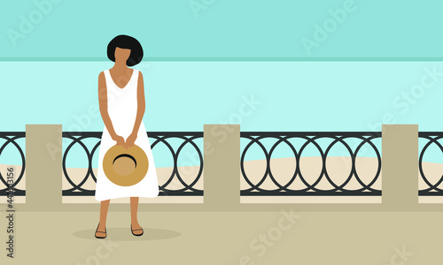 A female character in a white dress and with a hat in her hands stands on the embankment against the background of the sea