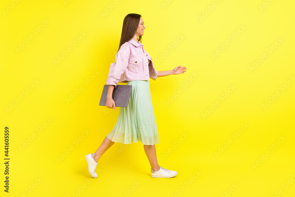 Full body profile photo of nice brunette hairdo young lady go with laptop wear spectacles pink shirt skirt isolated on yellow color background Full body profile photo of nice brunette hairdo young lady go with laptop wear spectacles pink shirt skirt isolated on yellow color background
