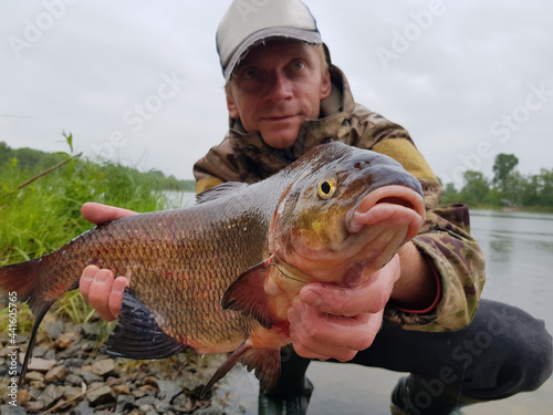 Fototapeta Naklejka Na Ścianę i Meble -  Happy fisherman holding a beautiful common bream.
