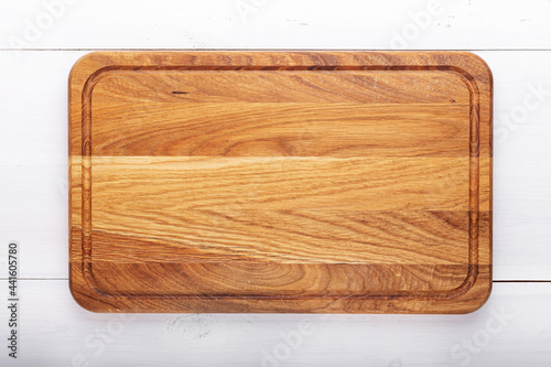 Rectangular cutting board on a white wooden table. Food preparation tool and kitchen utensils.
