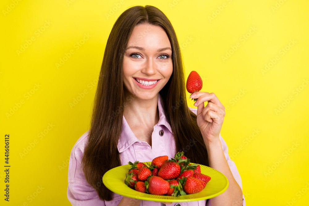 Photo portrait young woman keeping plate with strawberries happy cheerful isolated vibrant yellow color background Photo portrait young woman keeping plate with strawberries happy cheerful isolated vibrant yellow color background