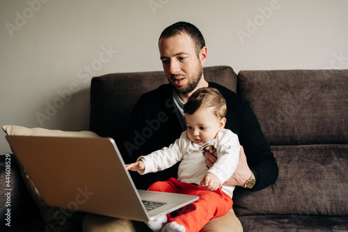 Young father with little son watching video on netbook photo