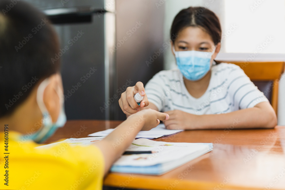 Elder sister applying hand sanitizer to her small brother to clean his hand. Elder sister applying hand sanitizer to her small brother to clean his hand.