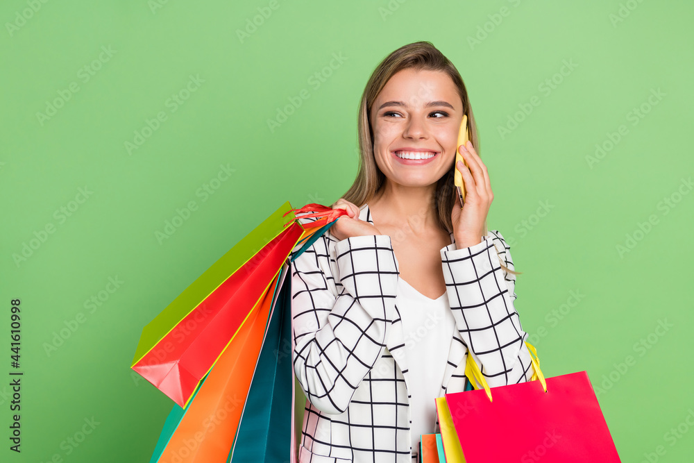 Portrait of attractive trendy cheerful girl carrying bags calling cellular isolated over bright green color background Portrait of attractive trendy cheerful girl carrying bags calling cellular isolated over bright green color background