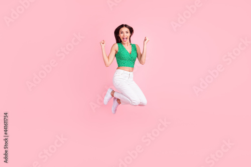 Full length body size photo smiling jumping up gesturing like winner isolated pastel pink color background