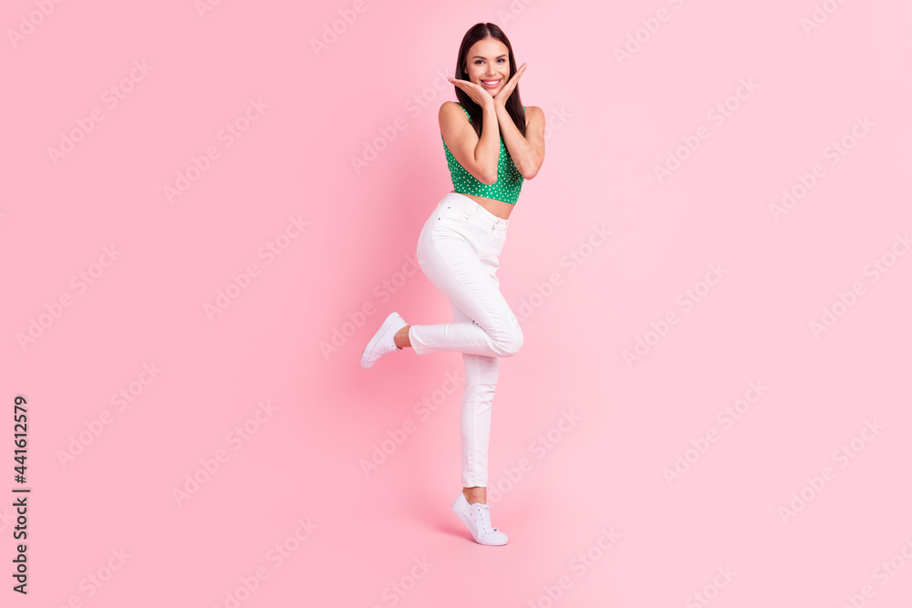 Full length body size photo smiling touching face woman in casual clothes isolated pastel pink color background Full length body size photo smiling touching face woman in casual clothes isolated pastel pink color background