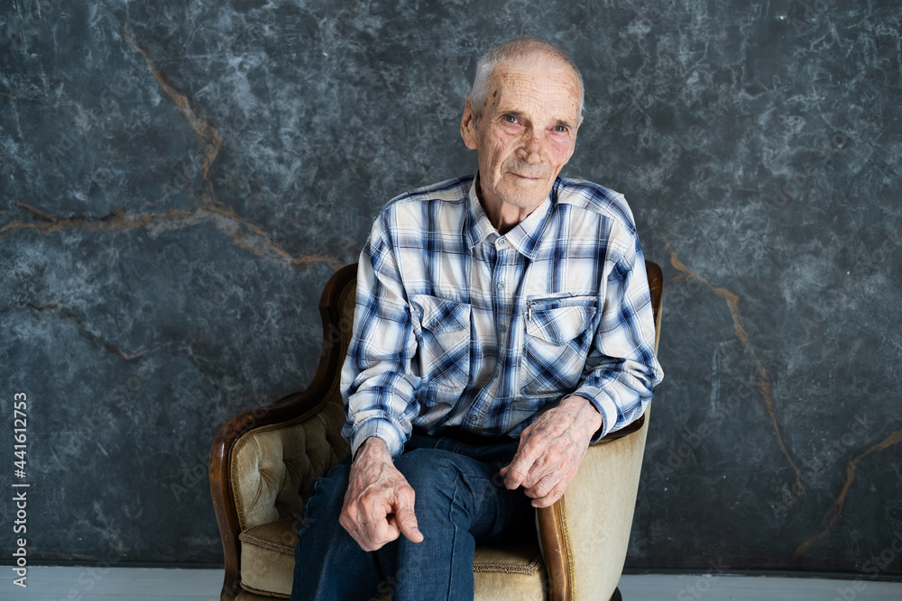 Portrait of elderly man sitting in chair in the room