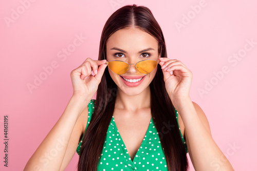 Photo of nice brown hairdo young lady hold spectacles wear green dotted top isolated on pink color background
