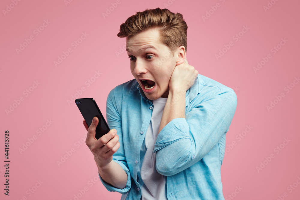 Shocked attractive male model surprised to receive text message, bad emotion Shocked attractive male model surprised to receive text message, bad emotion