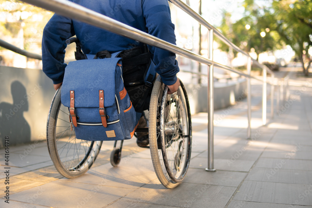 person in wheelchair with blue backpack arriving destination. person in wheelchair with blue backpack arriving destination.