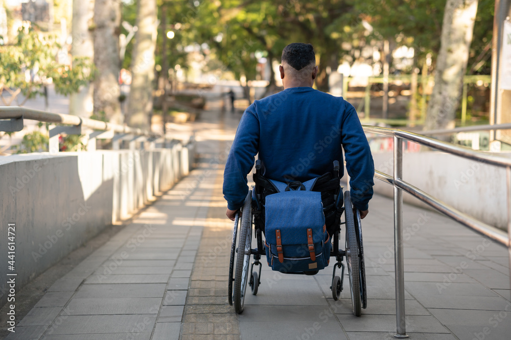 man in wheelchair starting to descend ramp.