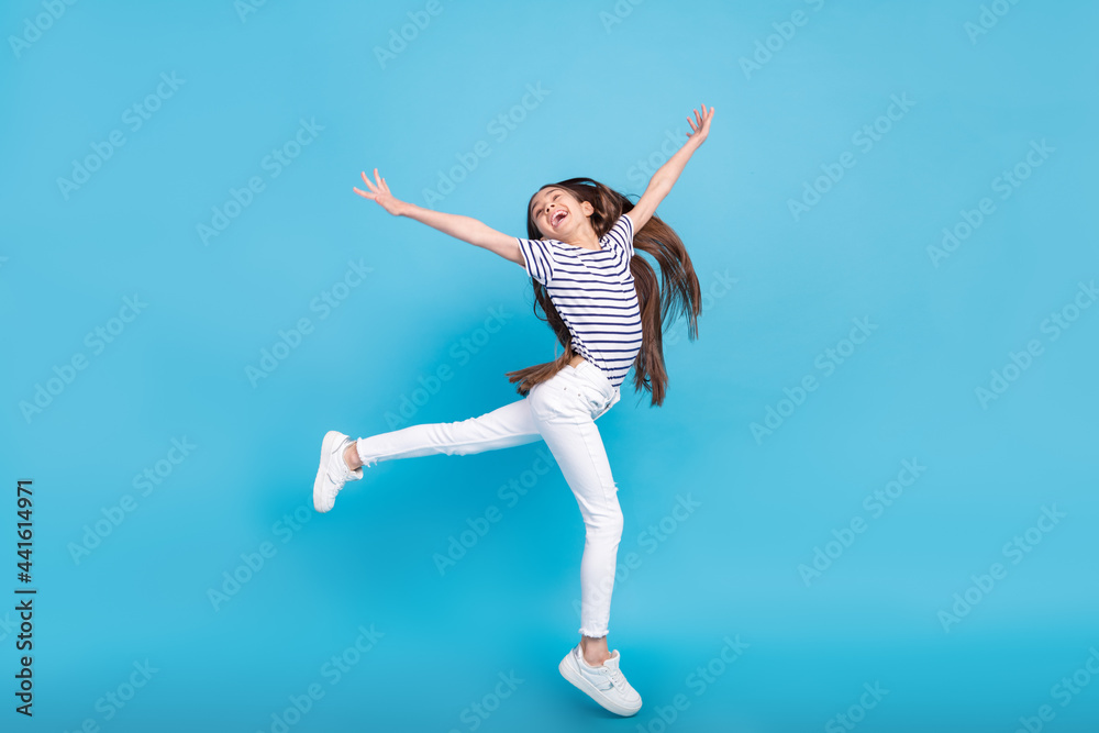 Full length profile side photo of young cheerful girl happy positive smile have fun isolated over blue color background Full length profile side photo of young cheerful girl happy positive smile have fun isolated over blue color background