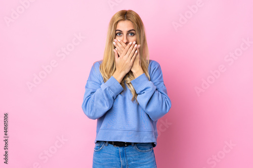 Young Uruguayan blonde woman over isolated pink background covering mouth with hands